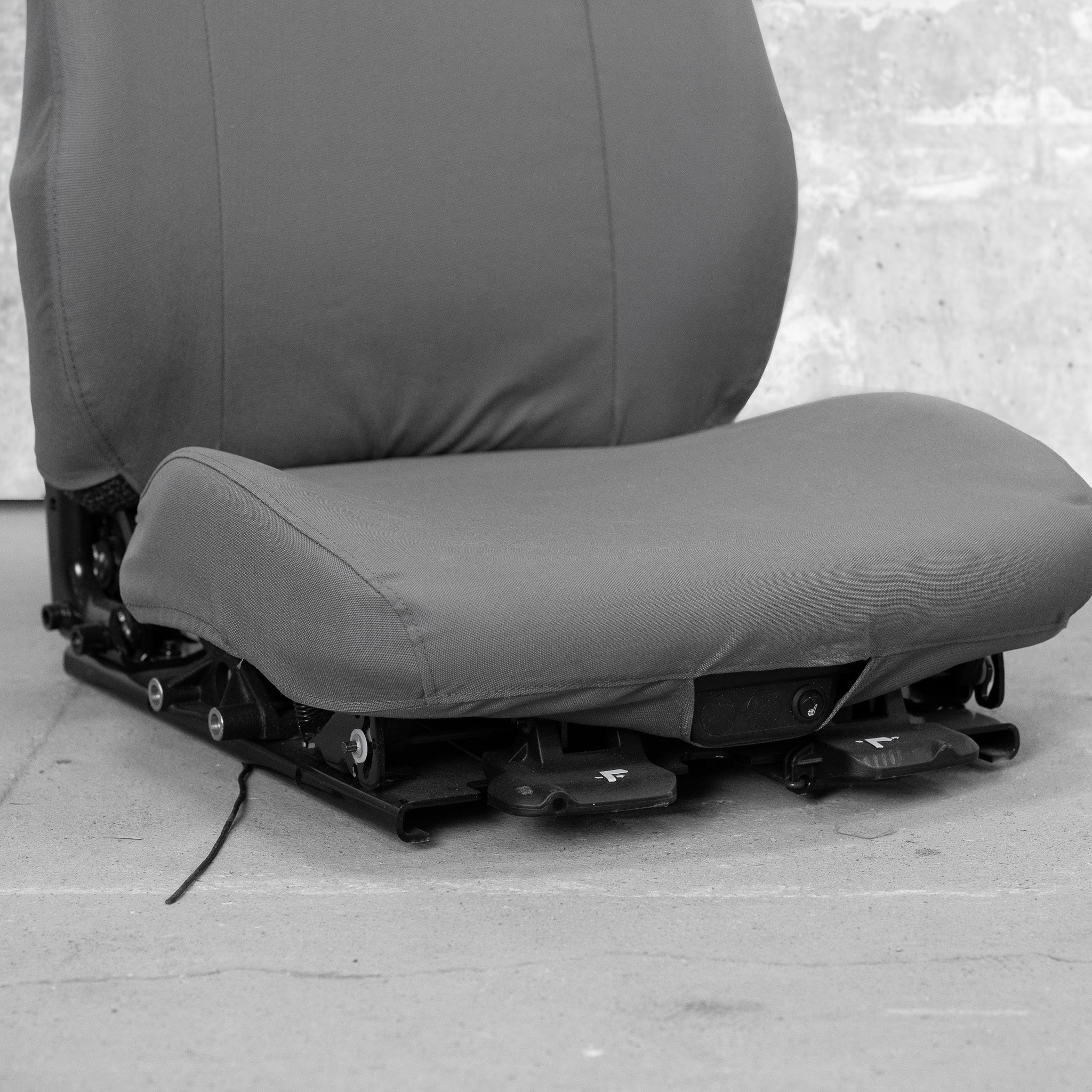 This is a close-up of the front seat bottom of a TigerTough heavy equipment seat cover. You can see how the seat cover works around the front seat controls.